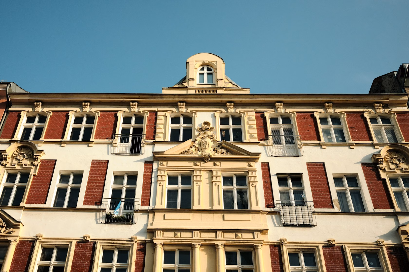Fachada clásica de un edificio completo con balcones y ventanas bajo cielo azul